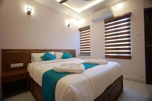 a bedroom with a large bed with two towels on it at TTS Residency in Kaliyal +16 photos
