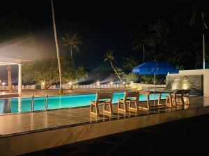 a table with chairs and an umbrella next to a swimming pool at Lavilla Lake Resort And Restaurant in Kollam