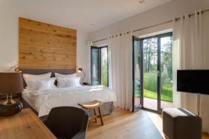 a bedroom with a bed and a tv and sliding glass doors at Hotel Strandhaus - Boutique Resort & Spa in Lübben