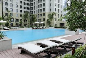 einen Pool mit Chaiselongues vor einem Gebäude in der Unterkunft SPACIOUS Home in Ho-Chi-Minh-Stadt