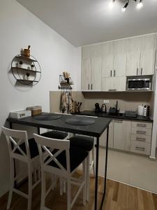 a kitchen with white cabinets and a black table and chairs at Tanasković Home Zlatibor in Zlatibor +16 photos