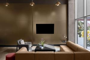 a living room with a couch and a tv at Cambria Hotel New York - Chelsea in New York