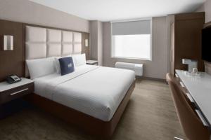 a bedroom with a large bed and a television at Cambria Hotel New York - Chelsea in New York