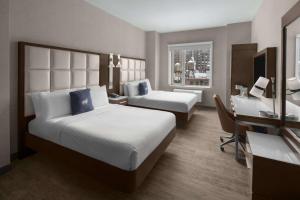 a hotel room with two beds and a desk at Cambria Hotel New York - Chelsea in New York +44 photos