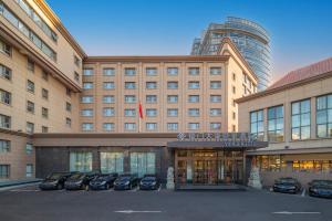 un grande edificio con auto parcheggiate di fronte di Beijing Xiamen Mansion Yihao Hotel a Pechino