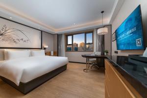 una camera d'albergo con un letto e una TV a schermo piatto di Beijing Xiamen Mansion Yihao Hotel a Pechino