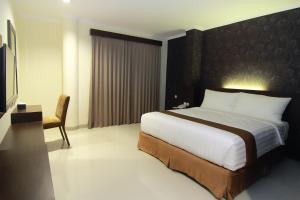 a bedroom with a large bed and a desk and chair at Nueve Malioboro Hotel Yogyakarta in Yogyakarta