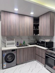 a kitchen with wooden cabinets and a washer and dryer at Le silver appartement 2 chambres in Libreville +15 photos