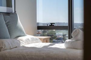 a bedroom with a white bed with a large window at Brand new Luxurious 1 Bedroom Perth CBD in Perth