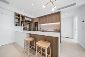a kitchen with a counter and two stools at Brand new Luxurious 1 Bedroom Perth CBD in Perth