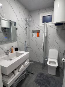 a white bathroom with a sink and a toilet at Le silver appartement 2 chambres in Libreville