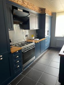 een keuken met blauwe kasten en een fornuis bij THE120 work or holiday home in Comines