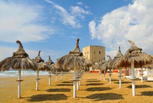 rząd słomianych parasoli na plaży w obiekcie Vacanze Romantiche a Modica w mieście Modica