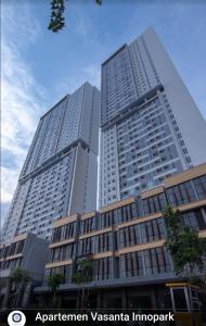 zwei hohe Gebäude in einer Stadt mit Bäumen davor in der Unterkunft Beautifull Vasanta Innopark Apartment 1BR -MM 2100 Cikarang Bekasi in Jarakasta