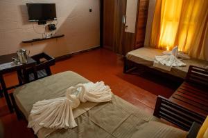 TaliparambaにあるBhavani Sarvashala - Holistic Wellness, Ayurveda & Physiotherapy Centreのベッド2台、テーブル、テレビが備わる客室です。