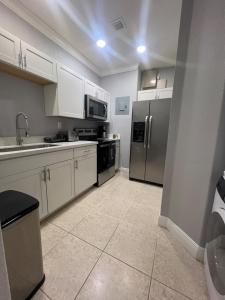 a kitchen with white cabinets and stainless steel appliances at Cozy Green Apartment in Homestead