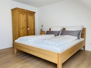 a large bed with white sheets and a wooden headboard at Ferienwohnung Haus Alpenblick in Lenzkirch
