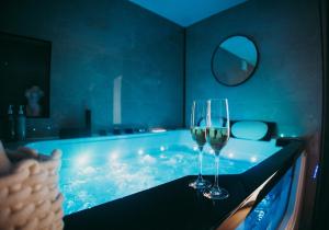 two wine glasses sitting on a table in a bath tub at FRENCH KlSS - Love Room by PRIM0 C0NCIERGERIE in Clermont-Ferrand