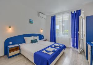 a blue and white bedroom with a bed and a window at Siyanie Kiten in Kiten