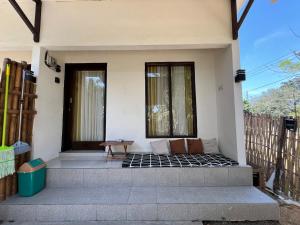 Un porche de una casa con un banco y dos ventanas. en B-local mong guest house, en Kuta Lombok 10 fotos más