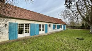 ein Gebäude mit blauen und weißen Türen und einem Hof in der Unterkunft Charmante longère - Havre de paix avec jardin et cheminée in Sallenelle