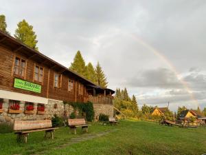a rainbow in the sky over a building with benches at Bungalovy Baranec in Žiar +29 photos