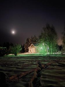a house in a field at night with the moon at Ainola Arctic Hillside in Rovaniemi