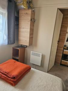 Un dormitorio con una cama con una manta naranja. en Mobilehome cosy, en Biscarrosse