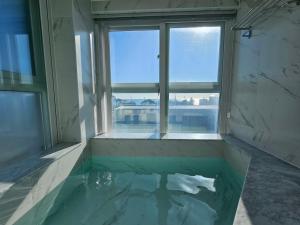 a room with a pool of water with a window at 펜톤나인 해변열차 송정2호점 in Busan
