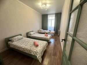 a room with two beds and a window and a door at Апартаменты на Ворошилова in Ustʼ-Kamenogorsk