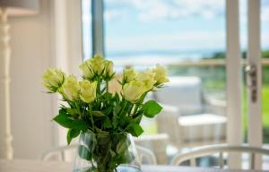 un vaso pieno di fiori gialli seduto su un tavolo di Muir Lodge a Gatehouse of Fleet