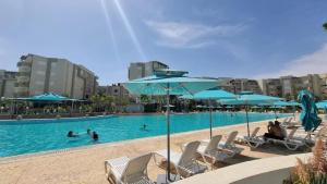 a pool with chairs and umbrellas and people in the water at Seasonal Rental S2 at Folla Palm Lake Monastir in Monastir