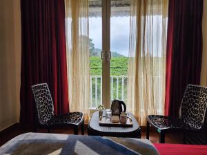 a bedroom with two chairs and a table and a window at Cloud & Mist Inn-Stay with Mountain Views in Kotagiri, Near Ooty in Kotagiri