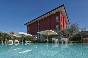 a swimming pool with chairs and umbrellas in front of a building at Vialeromadodici Rooms & Apartments in Lazise