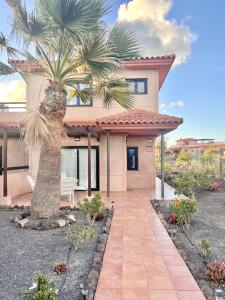 a house with a palm tree in front of it at Villa Majanicho Outside con piscina in Majanicho