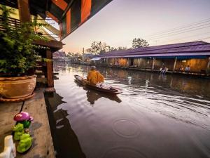 a man in a boat on a river at Baanklong Amphawa Homestay in Amphawa