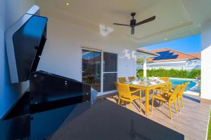 Un comedor con mesa y sillas y un televisor. en Brand-New Modern 3-Bedroom Villa - MB20, en Hua Hin