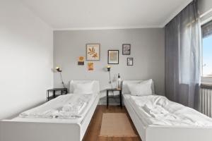 two beds in a room with white walls at Flatista Homes - Maisach in Maisach