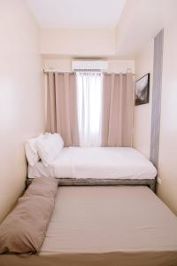 Dos camas en una habitación pequeña con ventana. en A Relaxing Poolside Stay, en Iloilo City