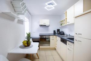 a kitchen with white cabinets and a pineapple on a table at FeWo 02 Maisonette im Carre`Charlott in Pulsnitz