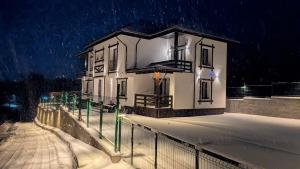 a white house with a fence in the snow at Conacu Lacului Brebu in Brebu Mînăstirei