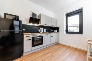 a kitchen with white cabinets and a black refrigerator at Monteurwohnung Dresden-Klotzsche I in Dresden +3 photos