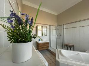 a bathroom with a large vase with purple flowers in it at Wohnperle*GroßerGarten*Villa in Dresden +17 photos