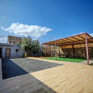 a pavilion with a wooden deck and a building at Sunrise Chalet شالية الشروق الجبل الاخضر in Duwaykhīlah