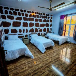 three beds in a room with a stone wall at Sunrise Chalet شالية الشروق الجبل الاخضر in Duwaykhīlah +22 photos