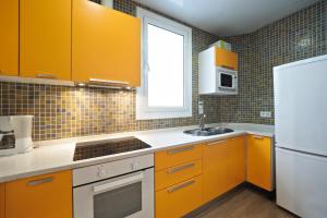 バルセロナにあるSuites4days Sagrada Familia Apartmentのキッチン(オレンジ色のキャビネット、白い冷蔵庫付)