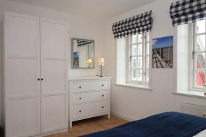 a bedroom with a bed and a dresser and two windows at Hüs Dikstian- Wohnung 5 in Alkersum