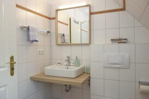 a white bathroom with a sink and a mirror at Hüs Dikstian- Wohnung 5 in Alkersum +15 photos