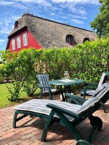 a patio with a table and chairs and a red barn at Hüs Dikstian- Wohnung 5 in Alkersum
