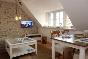 a living room with a table and a tv on a wall at Hüs Dikstian- Wohnung 5 in Alkersum
